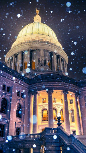 雪花輕輕飄落在夜間一座宏偉的、燈火通明的圓頂建築上。