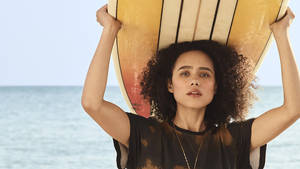 女性在海灘上將衝浪板高舉過頭頂