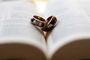 兩枚結婚戒指在打開的書頁上排列成心形。