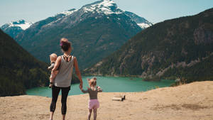 母親帶著嬰兒和幼女站在山丘上眺望山湖