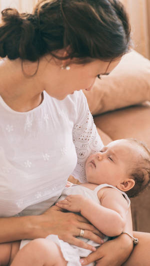 一位母親在舒適的室內環境中抱著她熟睡的嬰兒。