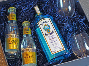 禮品套裝，包括氈酒、湯力水和酒杯，放在藍色碎紙盒中。