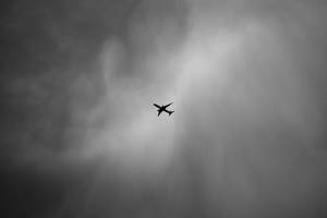 一架飛機在黑白多雲的天空中飛行。
