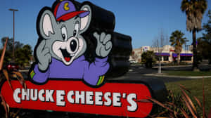 Chuck E Cheese 吉祥物雕像在陽光普照的日子於餐廳入口揮手。