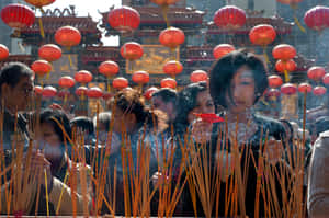 人們在掛有紅燈籠的寺廟內手持香枝祈禱。 — 中文 壁紙