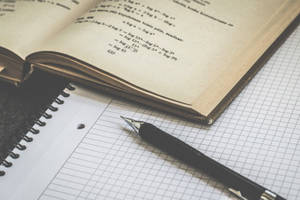 打開的數學書，方格紙上放著筆，用於學習