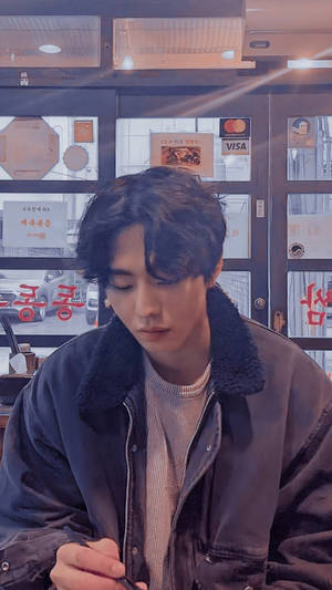 年輕男子穿著深色外套坐在咖啡館內低頭看 — Mikey 東京復仇者 GIF 壁紙