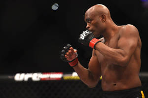 一名赤裸上身的MMA拳手在UFC八角籠內揮拳。
