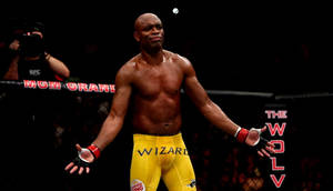 一位勝利的MMA拳手穿著黃色短褲，在八角籠中張開雙臂站立。