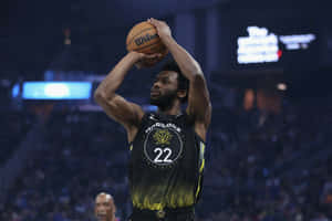 身穿勇士隊球衣的籃球運動員在比賽中準備投籃。