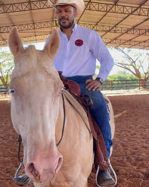 戴牛仔帽嘅男人喺有蓋競技場騎淺色馬。