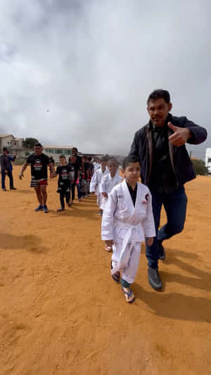 一名武術教練和小孩在塵土飛揚的場地上一起行走。