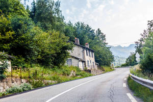 蜿蜒山路、石屋和森林覆蓋的山丘，天空明亮