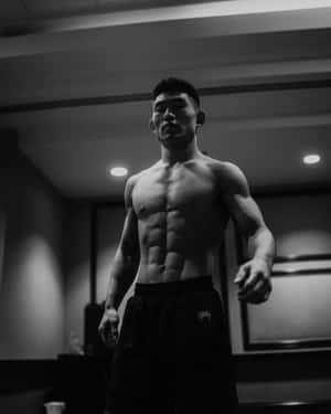 一個擁有清晰腹肌的肌肉男穿著短褲站在健身房裡。
