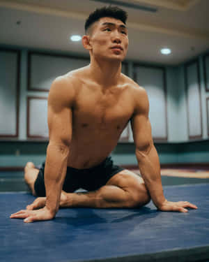 運動型男子在健身房藍色瑜伽墊上做瑜伽姿勢