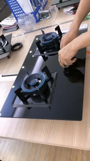 安裝帶有藍色火焰燃燒器的黑色玻璃煤氣爐的人。 — iPhone 7 壁紙