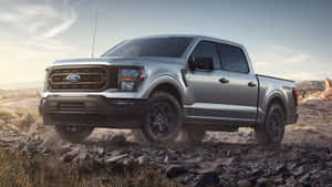銀色福特F-150卡車在黃昏時分穿越岩石沙漠地形。