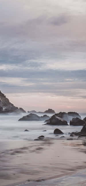 岩石海灘的黎明，平靜水流與粉彩天空