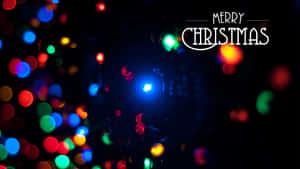 色彩繽紛的失焦聖誕燈飾，在黑暗背景上帶有「Merry Christmas」文字。 — 聖誕節桌面 壁紙