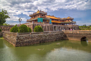 歷史宮殿建築群，擁有石牆和護城河，天空多雲。 — MacBook Pro M3 壁紙