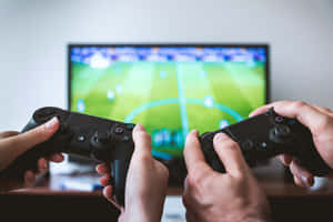 兩個人用控制器玩足球電子遊戲。 — PlayStation GIF 壁紙