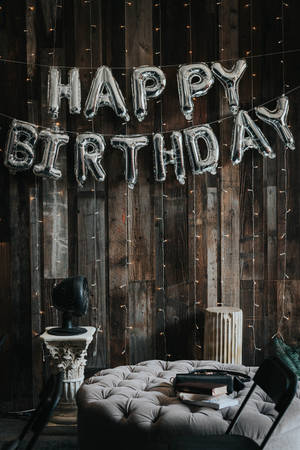 happy birthday氣球掛在帶有燈串的木牆上。