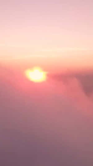 從空中俯瞰，朦朧雲層上帶有柔和粉紅色和橙色色調的日落