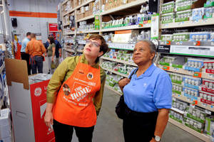 兩位女士在Home Depot商店通道選購燈泡。