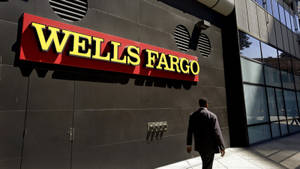 身穿西裝的男子走過 Wells Fargo 銀行大樓，帶有紅黃色標誌。