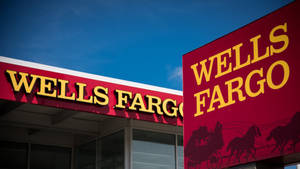 藍天下帶有紅色標誌和黃色字體的 Wells Fargo 銀行建築。