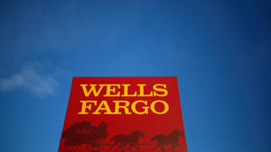 紅色Wells Fargo銀行標誌，帶有黃色文字和馬車剪影，襯托在藍天下。 — 晴朗天空 壁紙