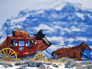 紅色 Wells Fargo 驛馬車由馬匹拉動穿越雪山。