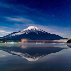 富士山在星空下的湖中倒映，遠處有燈光。 — iPad Air 13 壁紙