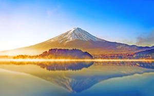 富士山倒映在霧氣繚繞的湖面上，日出時分，秋樹環繞