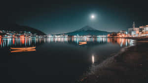 富士山上空的滿月，城市燈光和小船在平靜水面上的夜景