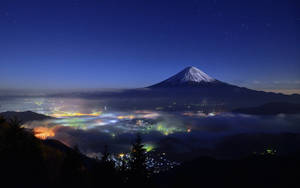 夜晚的富士山，下方是城市燈光，上方是星星
