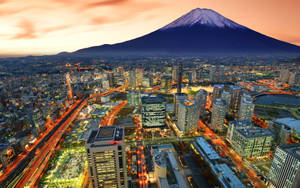 富士山俯瞰著日落時分閃爍的城市和流動的車燈。 — 東京卍復仇者 壁紙