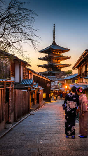 兩位身穿和服的女士在日本小鎮的夕陽下走向寶塔。