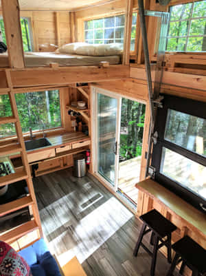 木屋內部，設有閣樓床、廚房，並透過玻璃門欣賞森林景觀。