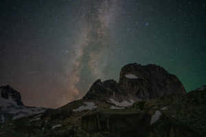 繁星點點的夜空，銀河系在積雪的山峰之上 — 星星 壁紙