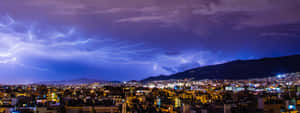 城市燈光在暴風雨的天空下閃耀，紫色閃電照亮雲層。