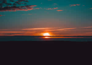 森林上空的夕陽，天空呈現橙色和藍綠色