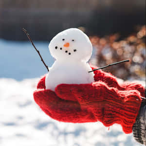 紅色手套嘅手捧住一個細雪人，喺白雪皚皚嘅冬天場景。