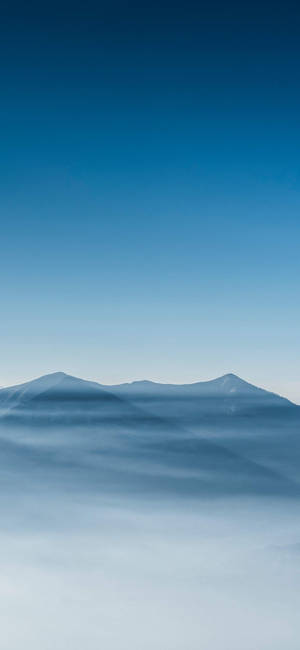 在晴朗藍天下從霧中浮現的山峰 — Galaxy S22 Ultra 壁紙