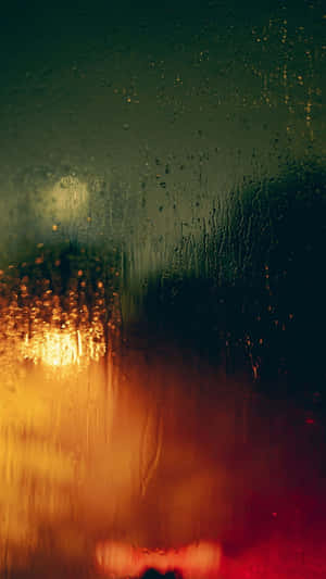 窗戶上的雨滴，夜晚模糊的溫暖城市燈光。