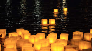 發光的燈籠在夜晚平靜的水面上漂浮，反射出金色光芒。