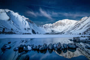 冰凍的湖面倒映著繁星夜空下的雪山。