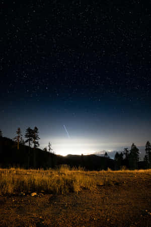 繁星點點的夜空，流星越過山脈和樹木 — 夜晚 GIF 壁紙