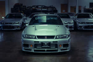 銀色日產Skyline R34 GT-R喺車庫入面同其他車一齊。 — 日產 Skyline GTR R33 壁紙