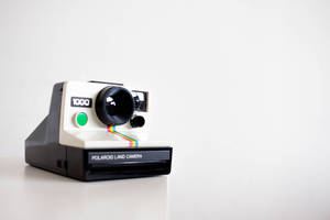 一部復古Polaroid Land Camera 1000相機，帶有彩虹菲林條，置於白色表面上。